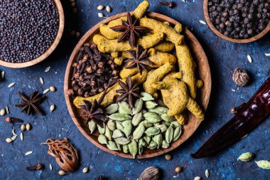 Koyu mavi beton arka planda, ahşap kaselerde ısıtılmış Hint baharatları. Egzotik vitamin, aroma, alternatif tıp, baharat, Ayurvedic. Yakın plan..