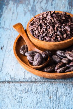 Organik çiğ kakao çekirdekleri, mavi kırsal arka planda ahşap kaseler, dikey çekimler, seçici odak noktaları..