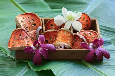 Kuru Bael meyvesi dilimleri muz yaprağının üzerindeki tahta kutuda..