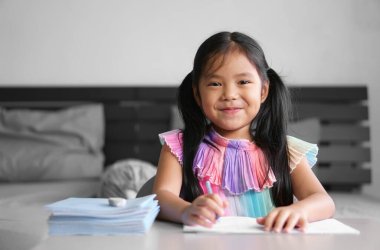 Asyalı çocuk öğrenci okula geri dönüyor ya da kız çocuk gülümsüyor. Yeni bir fikre ev ödevi yaparken mutlu bir şekilde kitap yazıyor ya da çiziyor ve okuyor. Ya da insanlar evde yatak odasında kitap yığınıyla ders çalışıyor.
