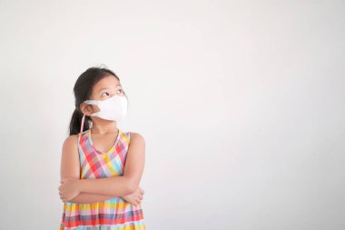 Asyalı çocuk kolları bağlanmış ya da N95 beyaz yüz maskesi takan çocuk burun ve grip hastalığı için başbakan 2.5 toz veya Coronavirus covid-19 'u korumak için öksürük hastalığına yakalanmış.