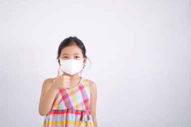 Asyalı çocuk başparmağını kaldırır ya da çocuk gülümsemesi takar. N95 beyaz yüz maskesi takar. Ağzı kapalı, grip olmuş, öksürük hastası olur.