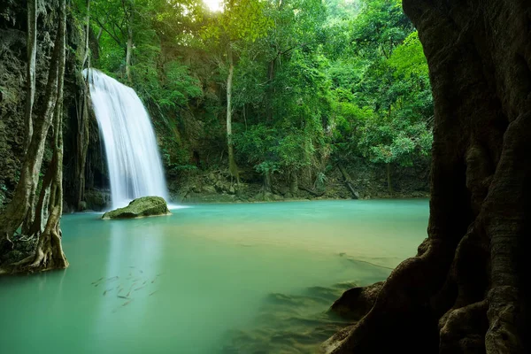 waterfall clear emerald water or blue pool with spa fish on summer season with rock and tree roots for holiday relax travel in green jungle or forest at erawan waterfall floor 3 for nature landscape