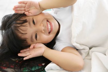 Asian children cute or kid girl sleep with open hand from eye for enjoy playing peekaboo or hide and seek with smile white teeth clipart
