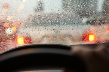 İnsanlar araba aynasında ya da ön camında yağmur fırtınası ve trafik sıkışıklığı olan araba ve su damlacıkları kullanıyor.