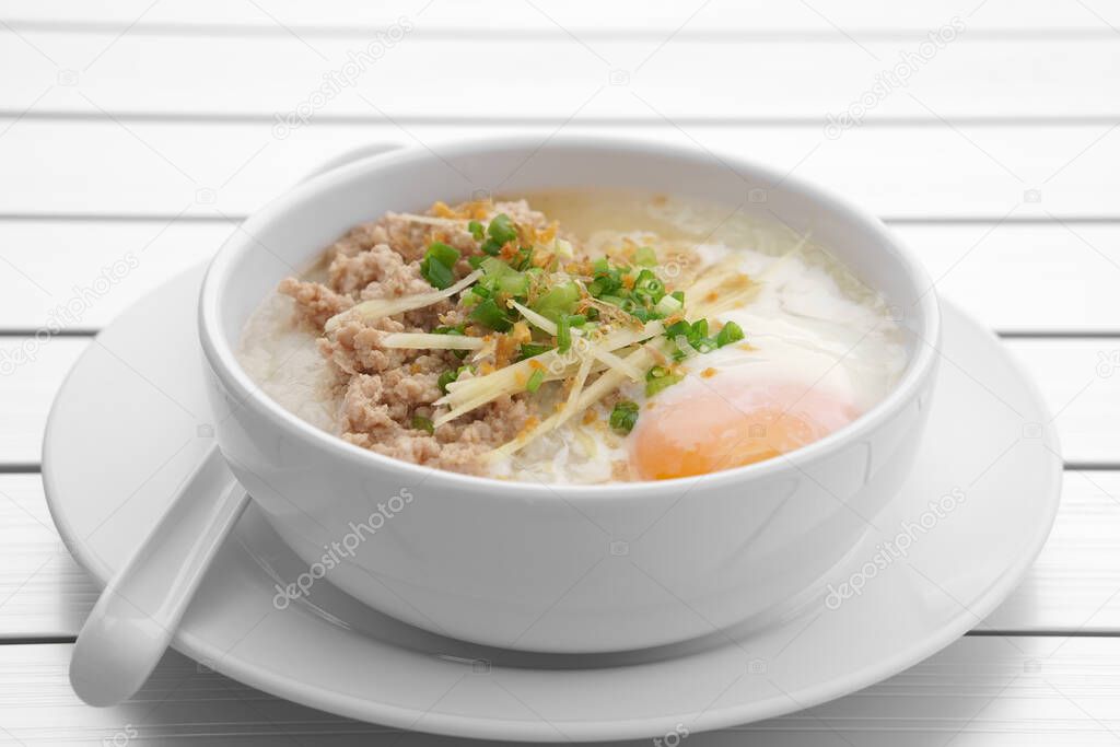 pork chops rice porridge or congee with soft boiled egg and vegetable in the white bowl with spoon on the aluminium table for delicious breakfast and clean food in the morning