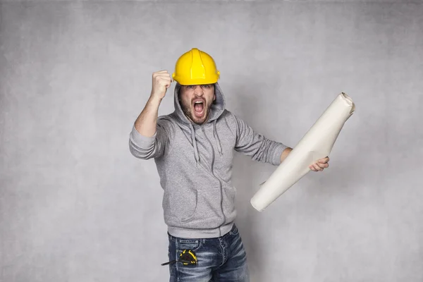 Angry builder holding blueprints in hand — 图库照片