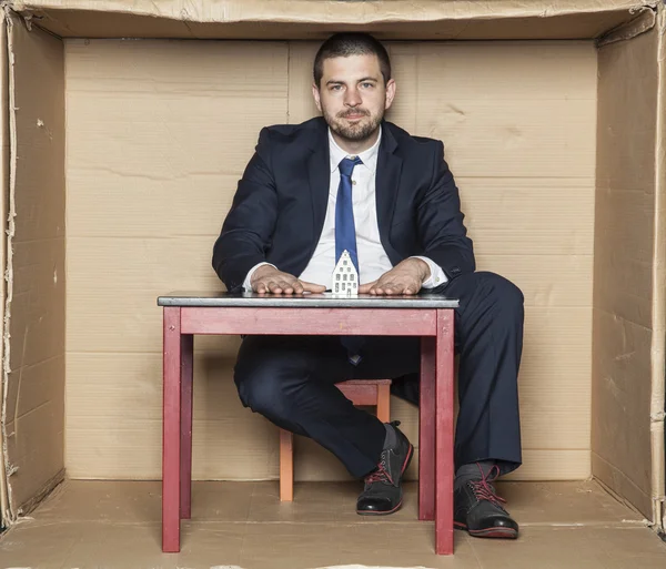 Hombre de negocios y su escritorio con una casa modelo —  Fotos de Stock