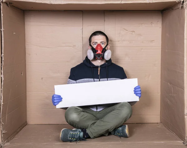 Hombre Una Máscara Protectora Sienta Una Caja Cartón Sostiene Cartel — Foto de Stock