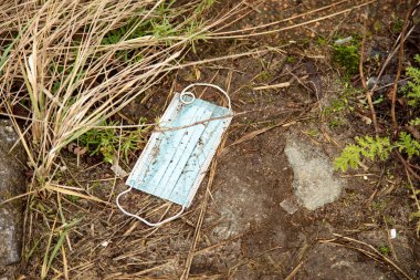 Koruyucu maske yerde yatıyor. Koronavirüs salgınının bir yan etkisi. Kullanılmış maskelerle ilgili büyük bir sorun. 