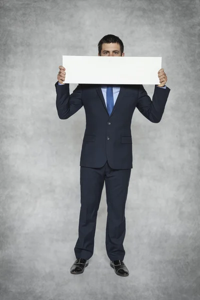 Businessman hiding behind a sheet of paper — Stock Photo, Image