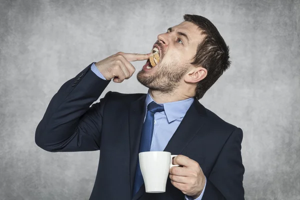 Hombre de negocios pone un sándwich en su boca — Foto de Stock