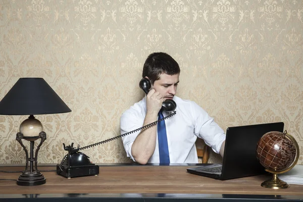 Homem de negócios trabalhando no laptop e falando ao telefone — Fotografia de Stock