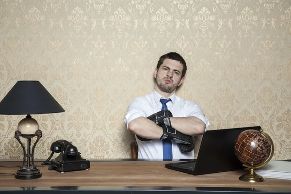 Бизнесмен в боксёрских перчатках сидит в офисе — стоковое фото