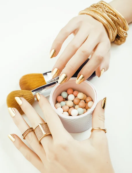 woman hands with golden manicure and many rings holding brushes, makeup artist stuff stylish, pure close up pink