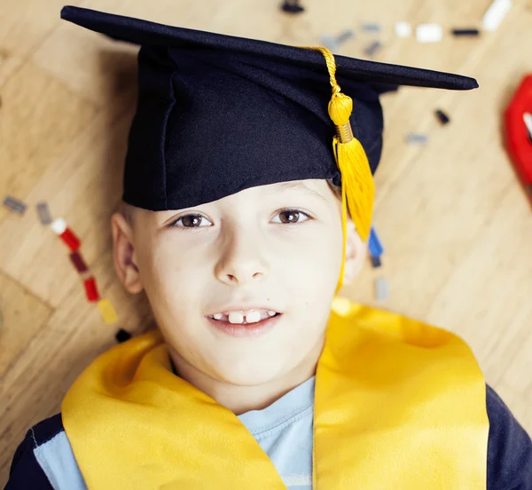 Little cute preschooler boy among toys at home in graduate hat smiling posing emotional, lifestyle people concept