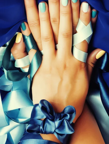 blue manicure with ribbon close up as a gift