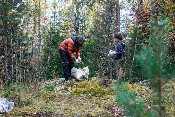 big amount of trash in forest, family father and son picking garbage away, global environment issues