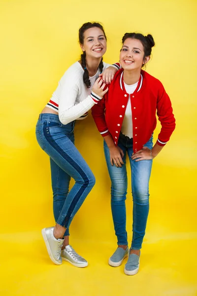 lifestyle people concept: two pretty young school teenage girls having fun happy smiling on yellow background