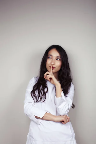 young asian woman doctor in white uniform gesturing positive on gray background, lifestyle healthcare people concept