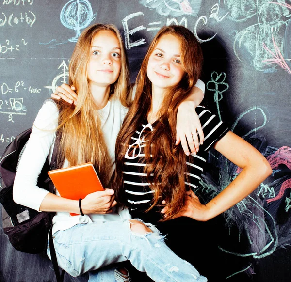 back to school after summer vacations, two teen real girls in classroom with blackboard painted together, lifestyle real people concept