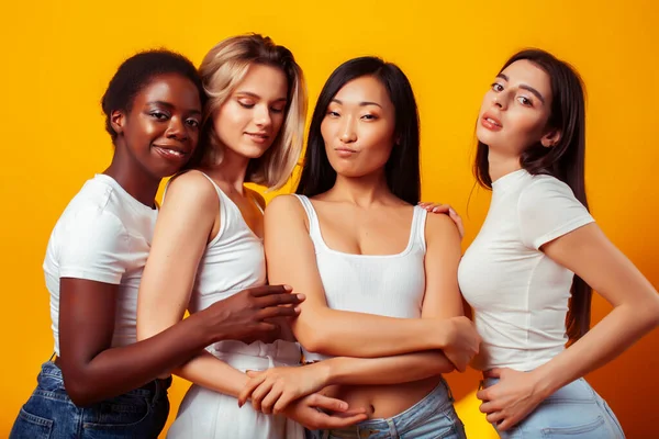 diverse multi nation girls group, teenage friends company cheerful having fun, happy smiling, cute posing on yellow background, lifestyle people concept, african-american, asian and caucasian