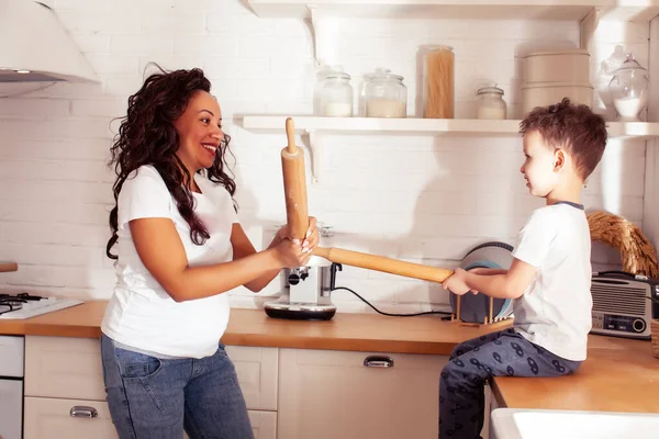 young pretty african american mother with little cute son on kitchen in morning preparing breakfast, lifestyle people concept