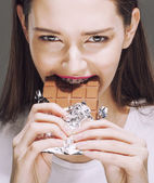 niedliche junge Frau mit Schokolade aus nächster Nähe essen