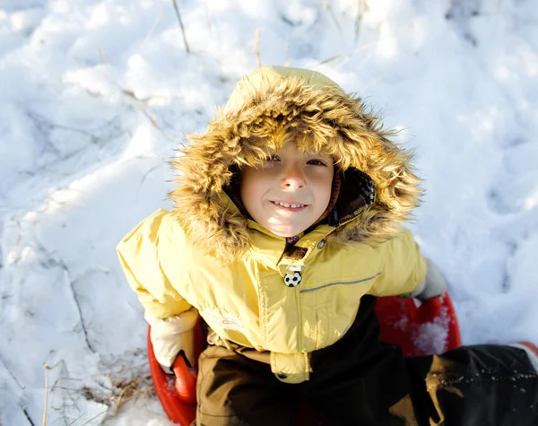 little cute boy in hood with fur on snow outside
