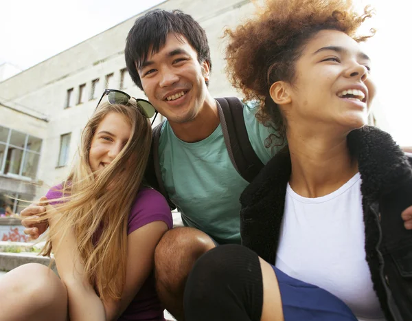 cute group of teenages at the building of university with books huggings, back to school