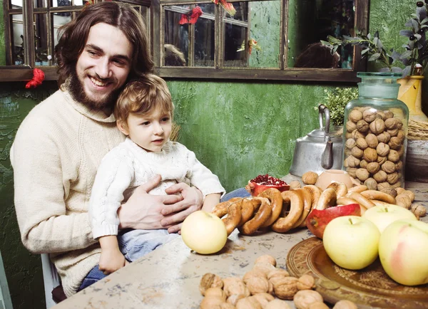 father with beard holding son at countryside vintage kitchen