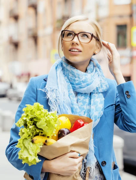 young pretty blond woman with food in bag walking on street
