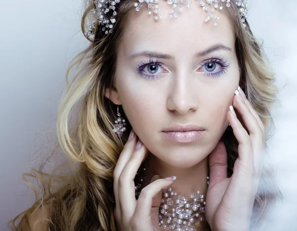 beauty young snow queen in fairy flashes with hair crown on her head close up