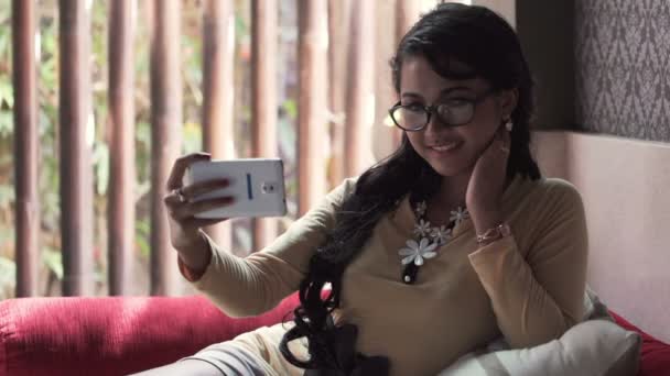 Женщина делает селфи с телефоном на диване — стоковое видео