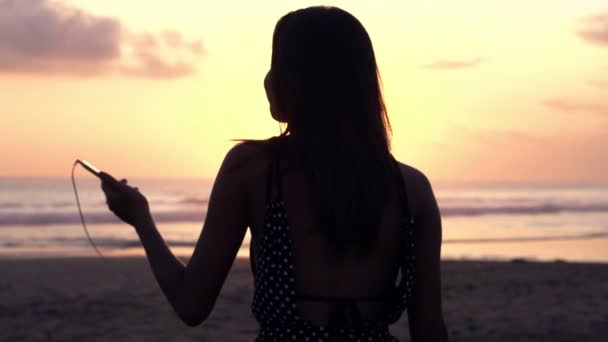 Mujer escuchando música en la playa — Vídeos de Stock