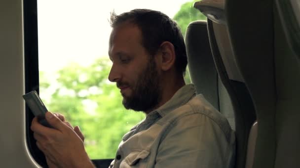 Hombre con teléfono inteligente moderno sentado en un tren — Vídeos de Stock