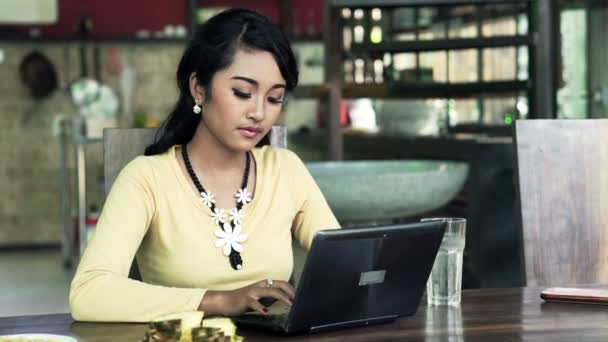 Nő használ laptop asztal mellett ülve — Stock videók