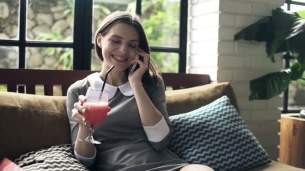 Woman talking on cellphone and drinking cocktail — Stock Video