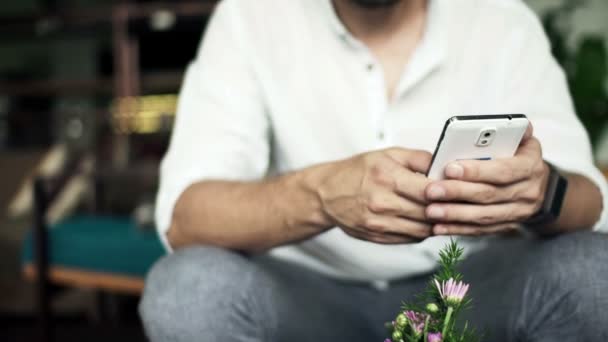 Man met smartphone op de bank — Stockvideo