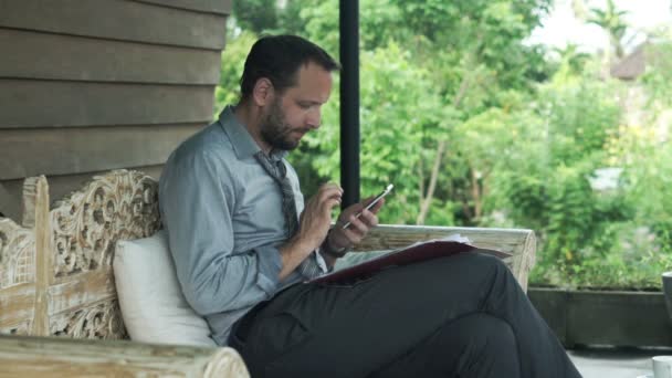 Geschäftsmann arbeitet mit Smartphone und Dokumenten — Stockvideo