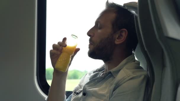 Hombre beber jugo de naranja durante viaje en tren — Vídeos de Stock