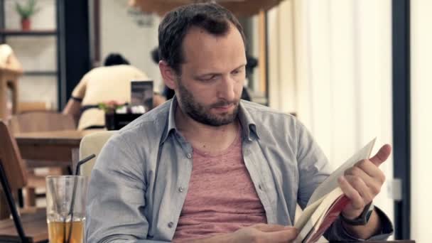 Мужчина читает книги и пьет коктейли — стоковое видео