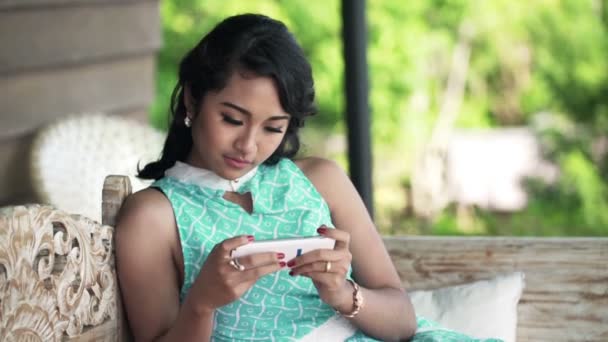 Woman using smartphone while sitting on sofa on terrace — Stock Video