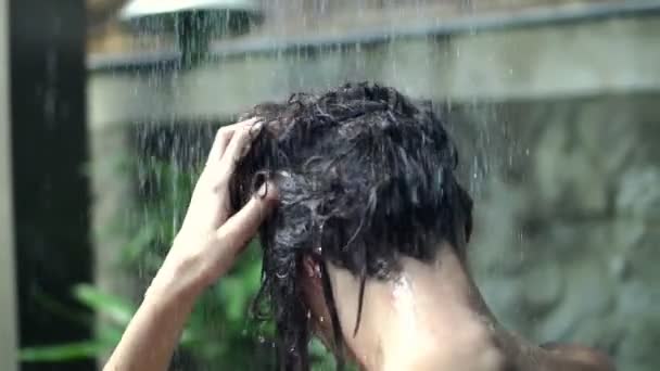 Jovem mulher lavando o cabelo sob chuveiro — Vídeo de Stock