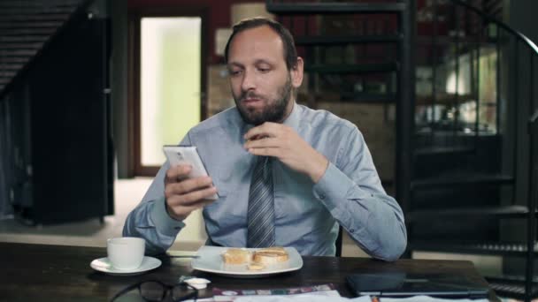 Affärsman med smartphone äter frukost — Stockvideo