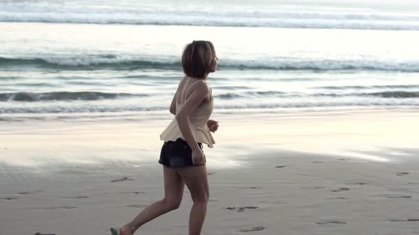 Жінка біжить уздовж пляжу — стокове відео
