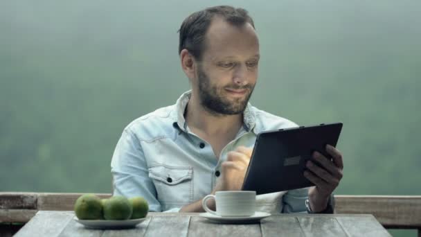 Mann benutzt Tablet und trinkt Kaffee — Stockvideo