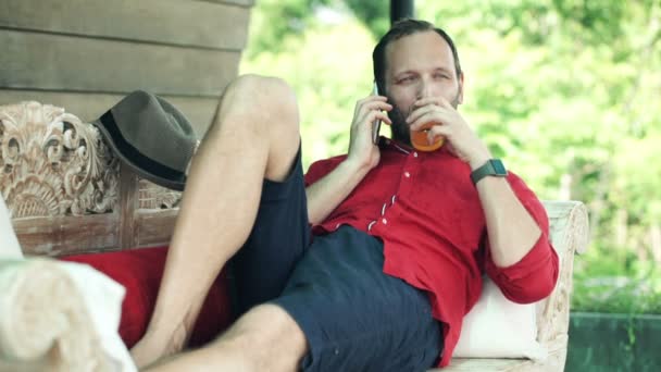 Man talking on cellphone and drinking beverage — Stock Video