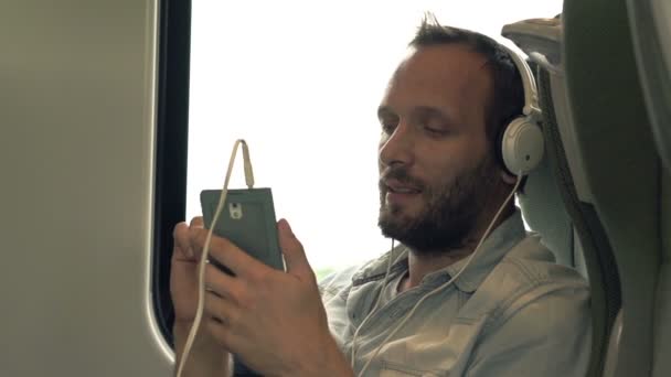 Adam dinleme ve müzik için tren yolculuğu sırasında şarkı — Stok video