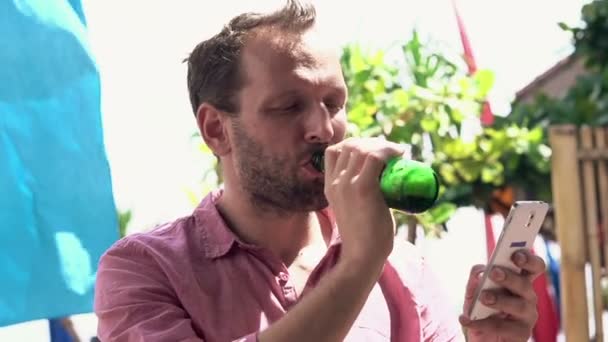 Mann mit Smartphone trinkt Bier in Bar — Stockvideo